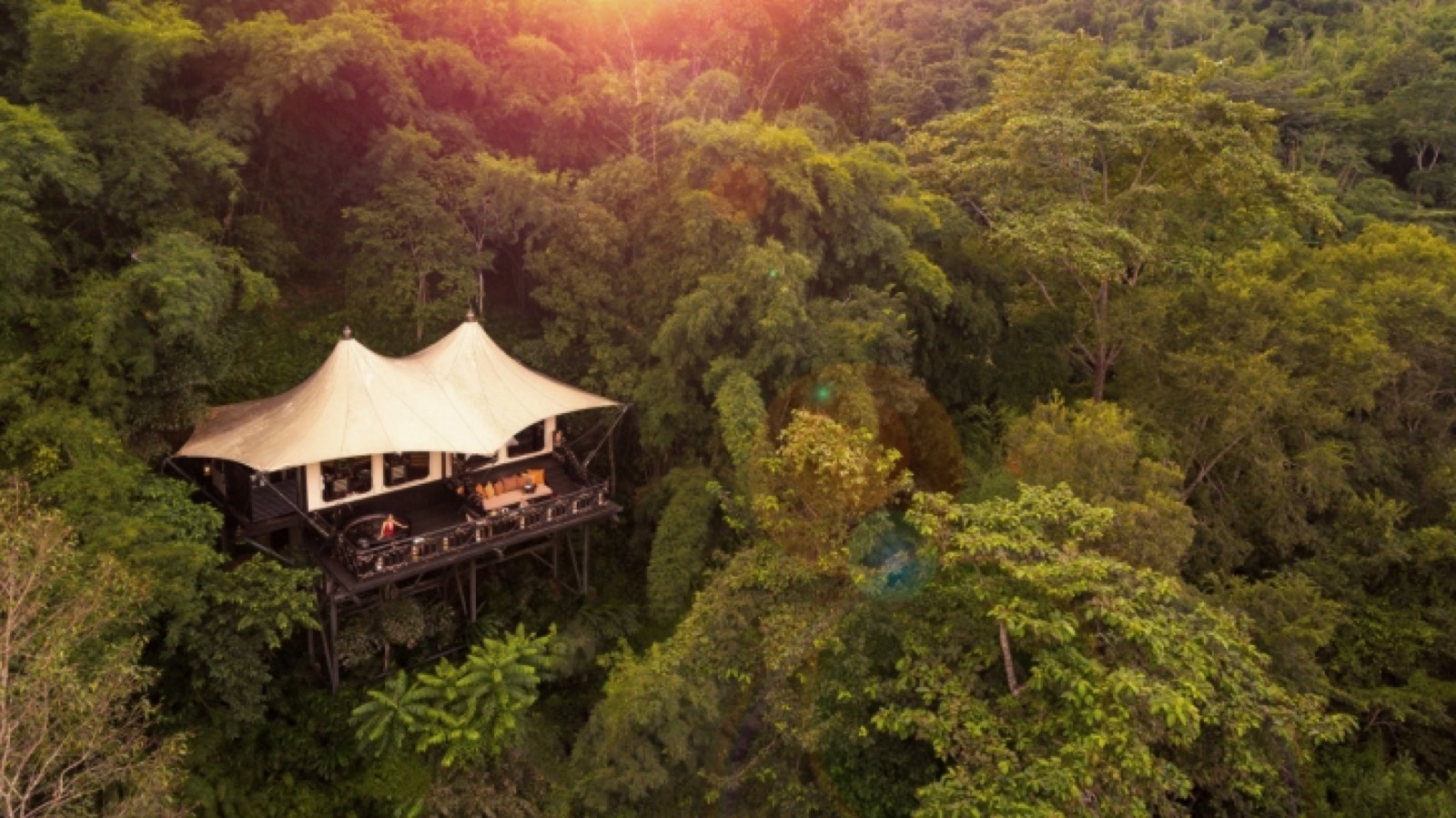 A twin-peaked tented suite raised on stilts above the jungle canopy at sunset, Four Seasons Tented Camp Golden Triangle