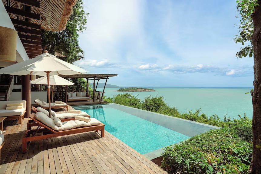 An infinity pool on a headland with sun loungers, a small island visible across the Gulf, Six Senses Samui