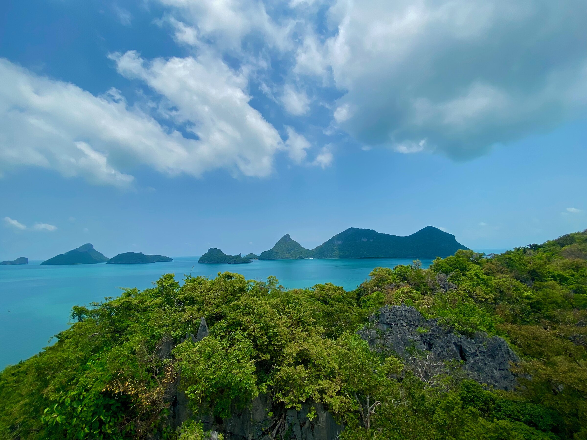 Forested limestone islands of Ang Thong Marine Park under a blue sky, seen from a high point