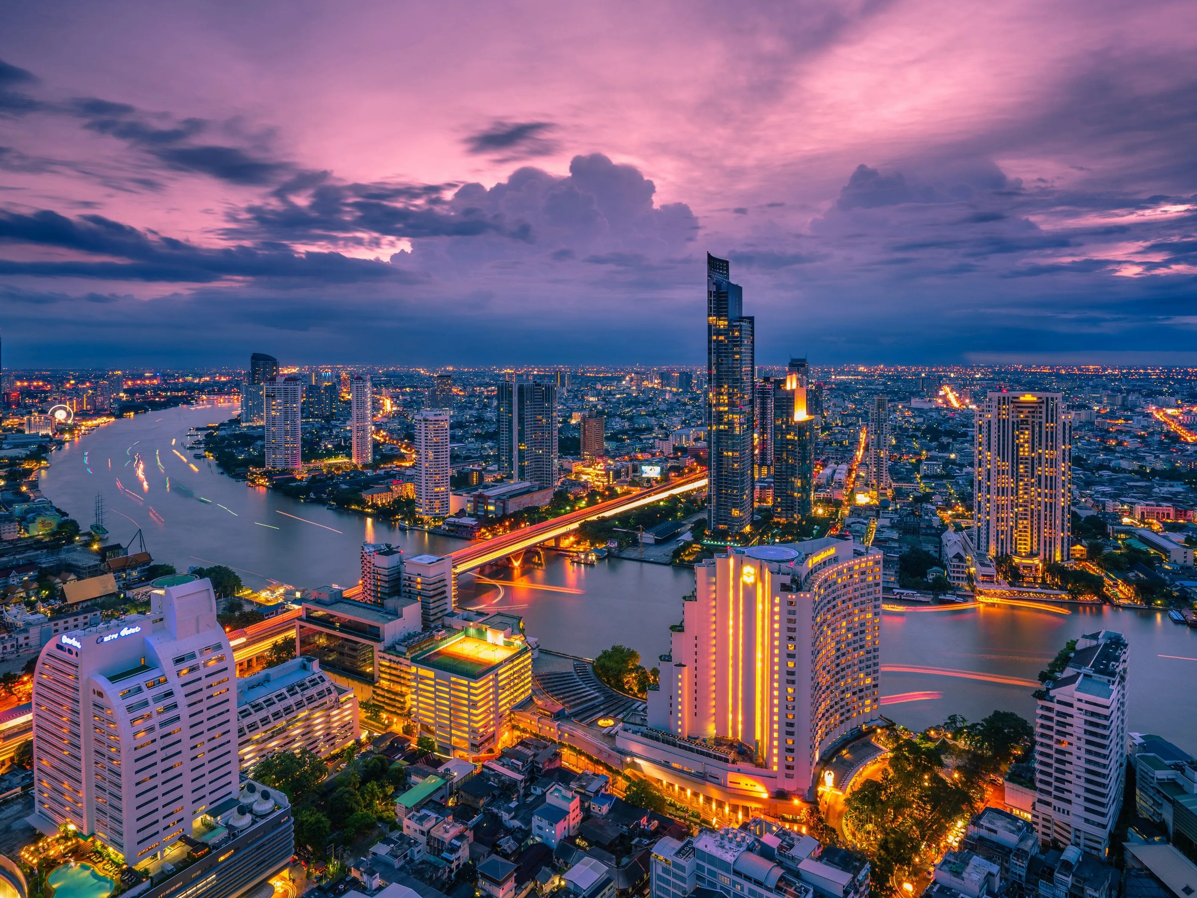 Bangkok’s skyline and the Chao Phraya at dusk, the river lit as it bends through the city